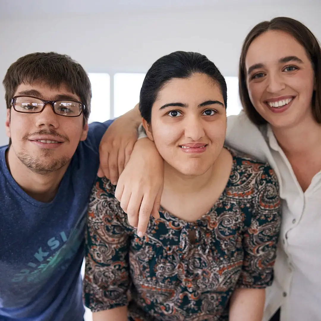 Drei junge Menschen stehen eng beieinander, lächeln in die Kamera und strahlen Zusammenhalt aus – ein starkes Bild für gelebte Inklusion und ein inspirierendes Umfeld für ein Praktikum bei der Lebenshilfe Herford.