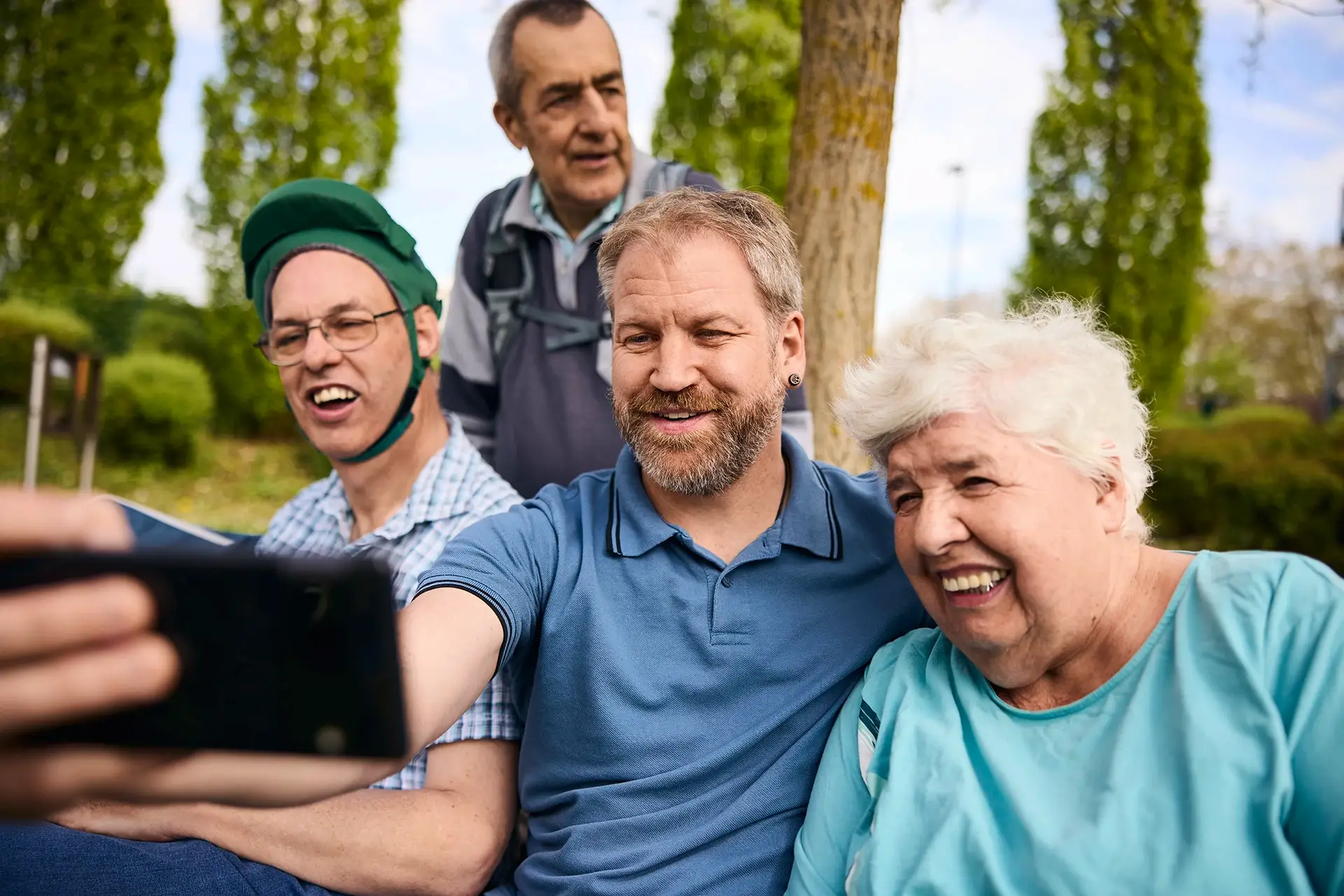 Eine fr&ouml;hliche Gruppe macht gemeinsam ein Selfie im Gr&uuml;nen &ndash; ein authentischer Einblick in das wertsch&auml;tzende Miteinander und die gelebte Inklusion, wie sie bei den Stellenangeboten der Lebenshilfe Herford im Mittelpunkt stehen.