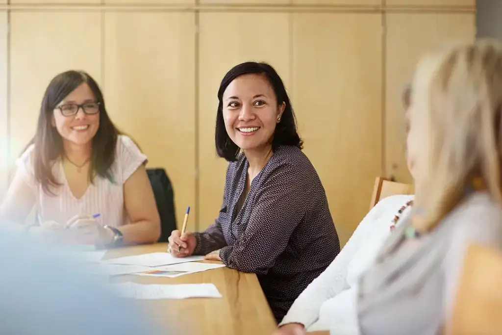 Mehrere Frauen sitzen gemeinsam an einem Tisch, tauschen sich aus und lachen – ein Blick hinter die Kulissen der Teamarbeit und des wertschätzenden Miteinanders, wie es die Stellenangebote der Lebenshilfe Herford ermöglichen.