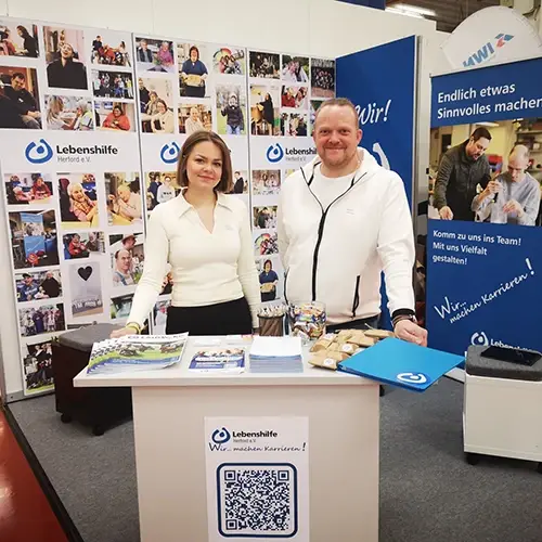 Zwei Mitarbeiter der Lebenshilfe Herford am Messestand.
